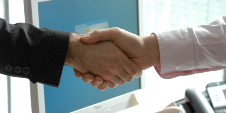 A handshake over a computer.