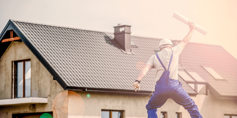 A contractor jumping in front of a house.