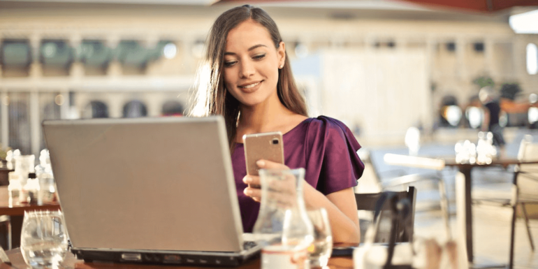 A woman on a laptop and a phone.